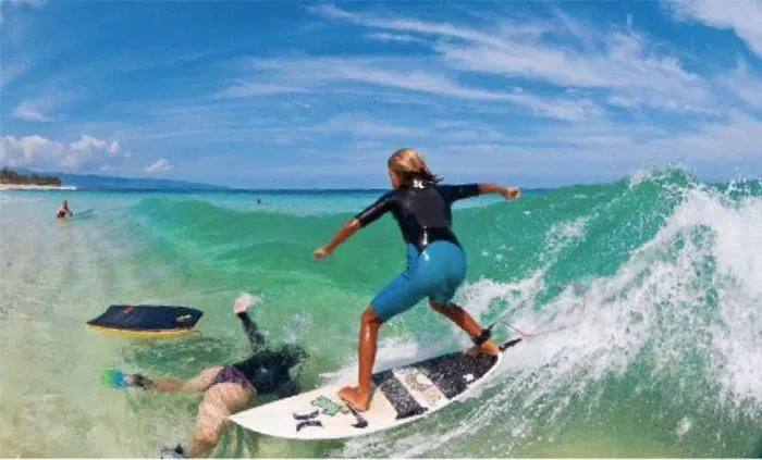 kid-riding-surfboard-on-by-fat-body-boarder.webp